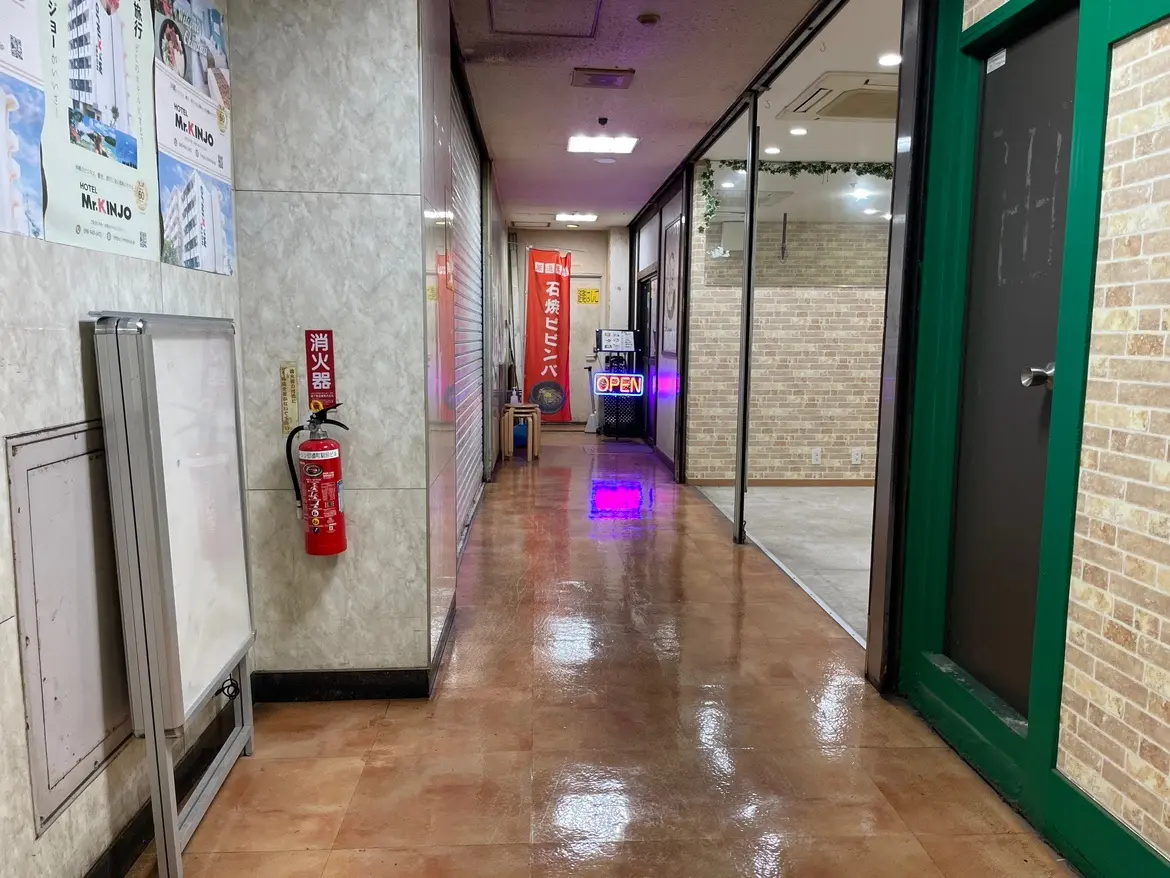 照明が設置された商業ビルの内廊下、案内看板と消火器が壁に取り付けられている