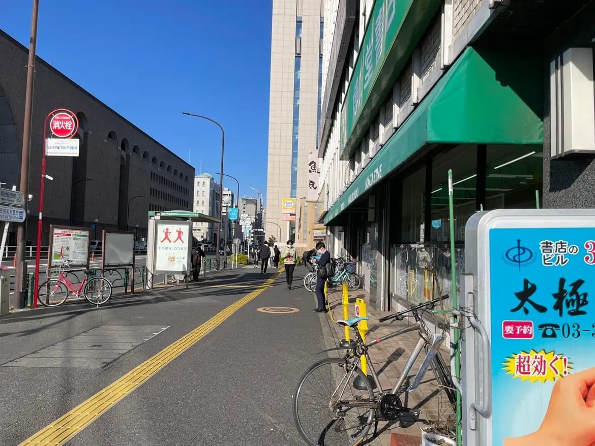 晴れた日の都市風景、バス停と自転車が置かれた歩道、背景にビルと店舗のファサード