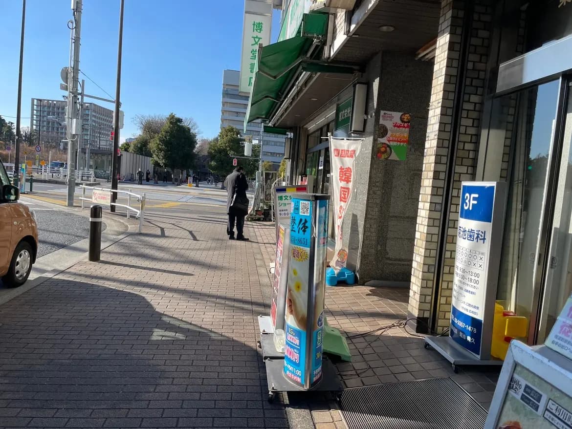 晴れた日の日本の街角、歩道と道路、歩行者と店舗の外観