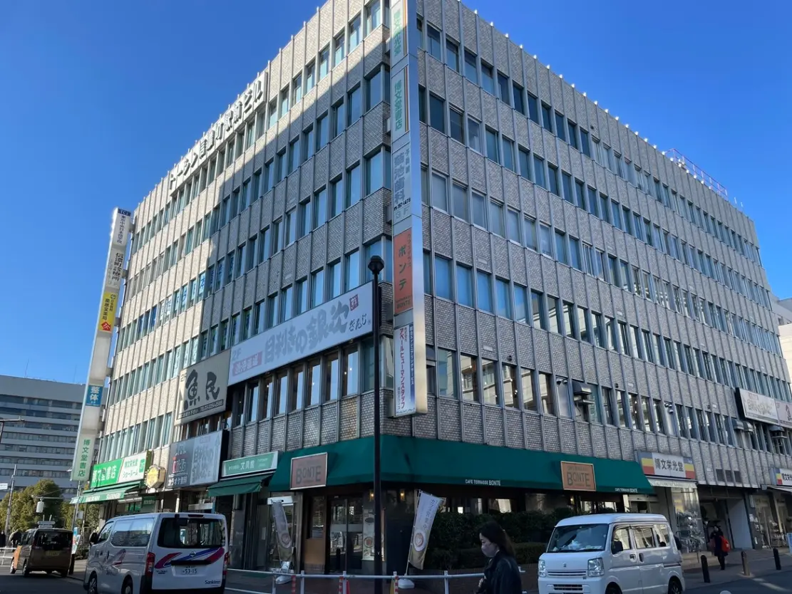日中の都市通りの風景、モダンなビルのファサード、店舗の看板、晴天の下