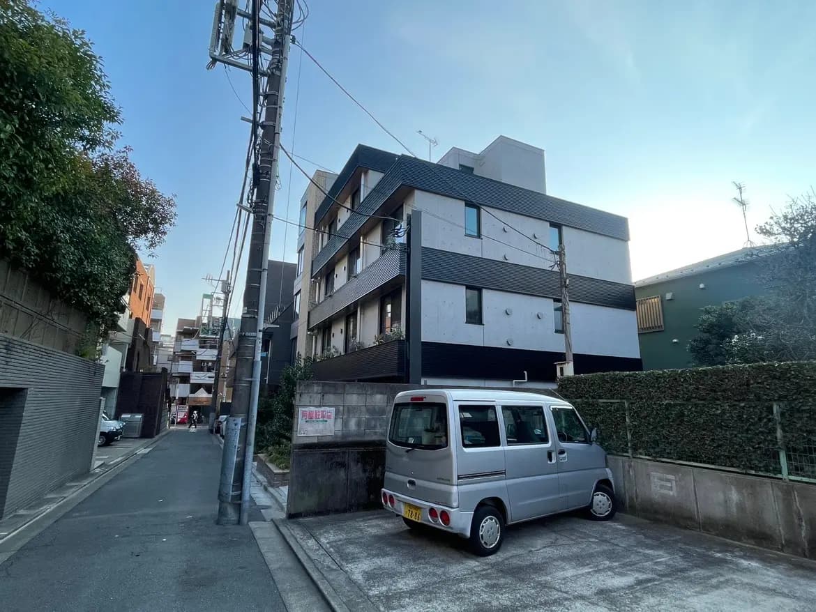 日本の住宅街の風景、モダンな建物と路上駐車された軽自動車、電信柱と青空