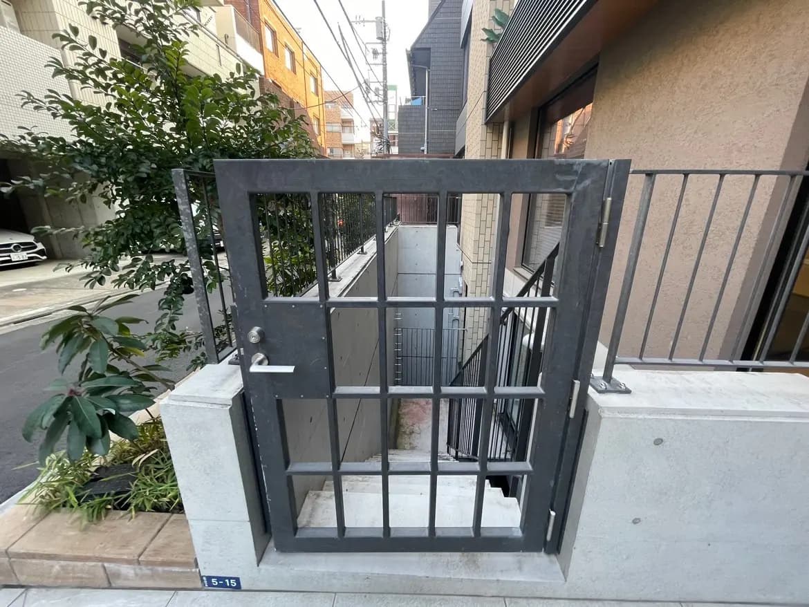 都市の住宅街にあるモダンな外観のアパートの入り口と黒い手すりの階段