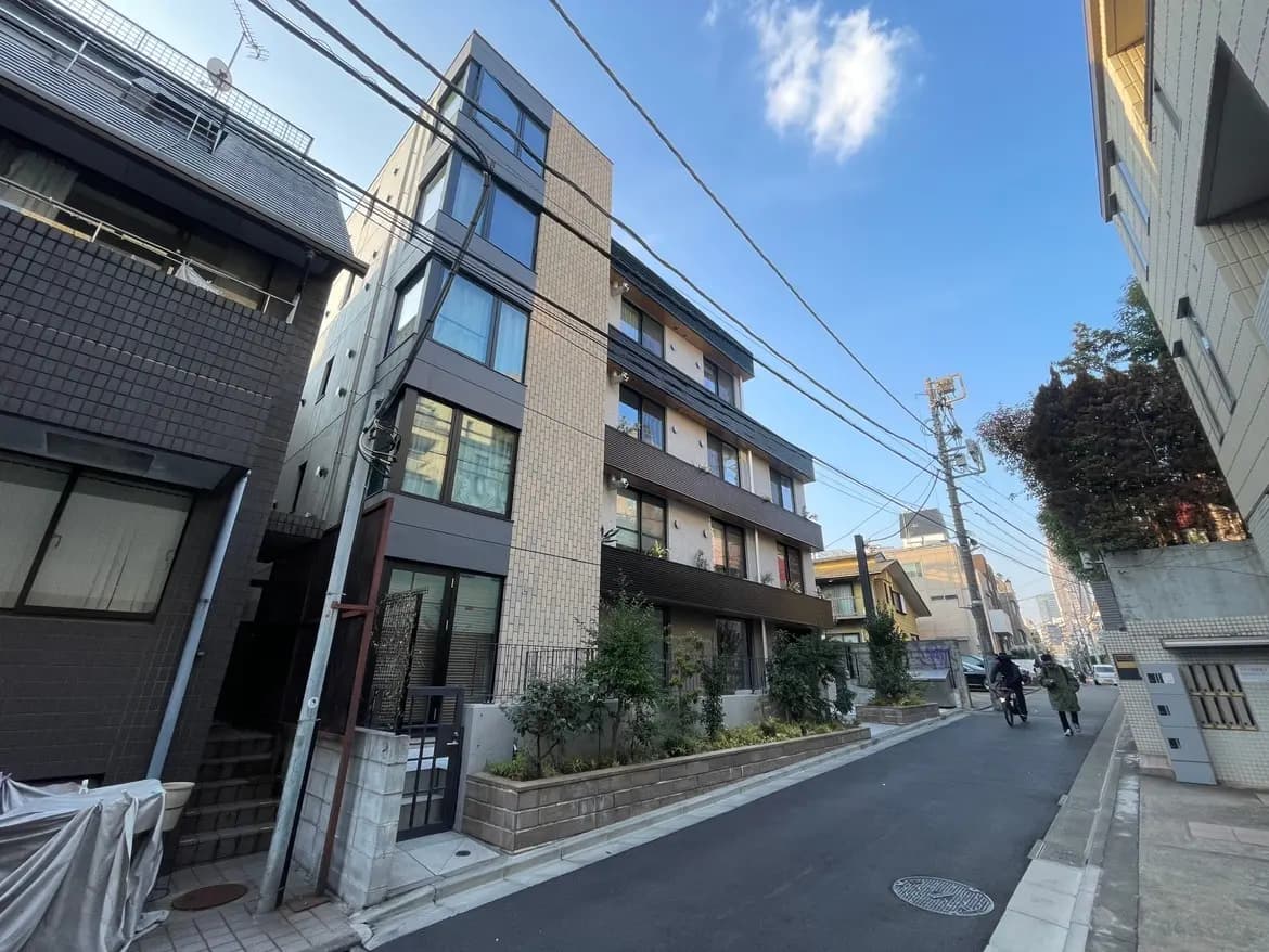 都市の住宅街にあるモダンなアパート建物、清潔感のある歩道、自転車を利用する人々