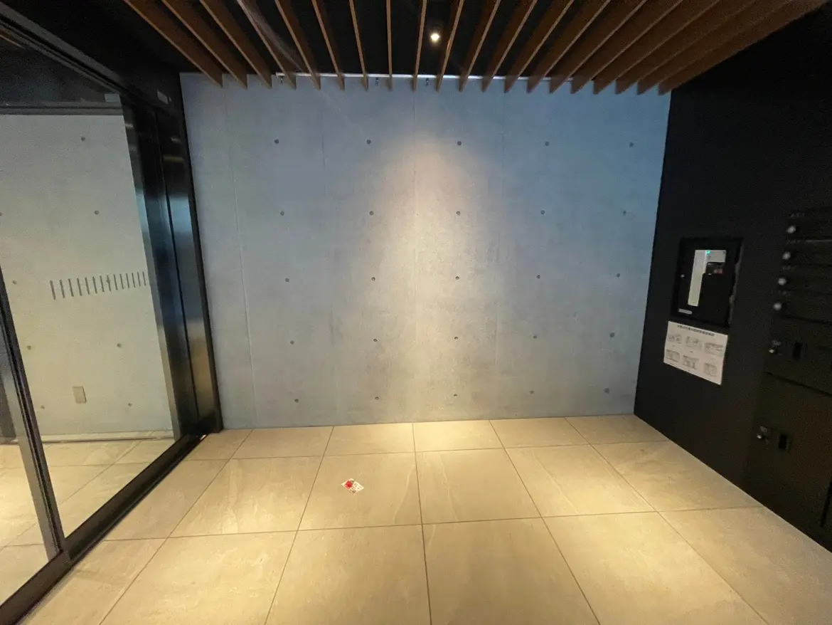 モダンな建築スタイルのエントランスエリア、コンクリートの壁、木製の梁、タイルフローリング