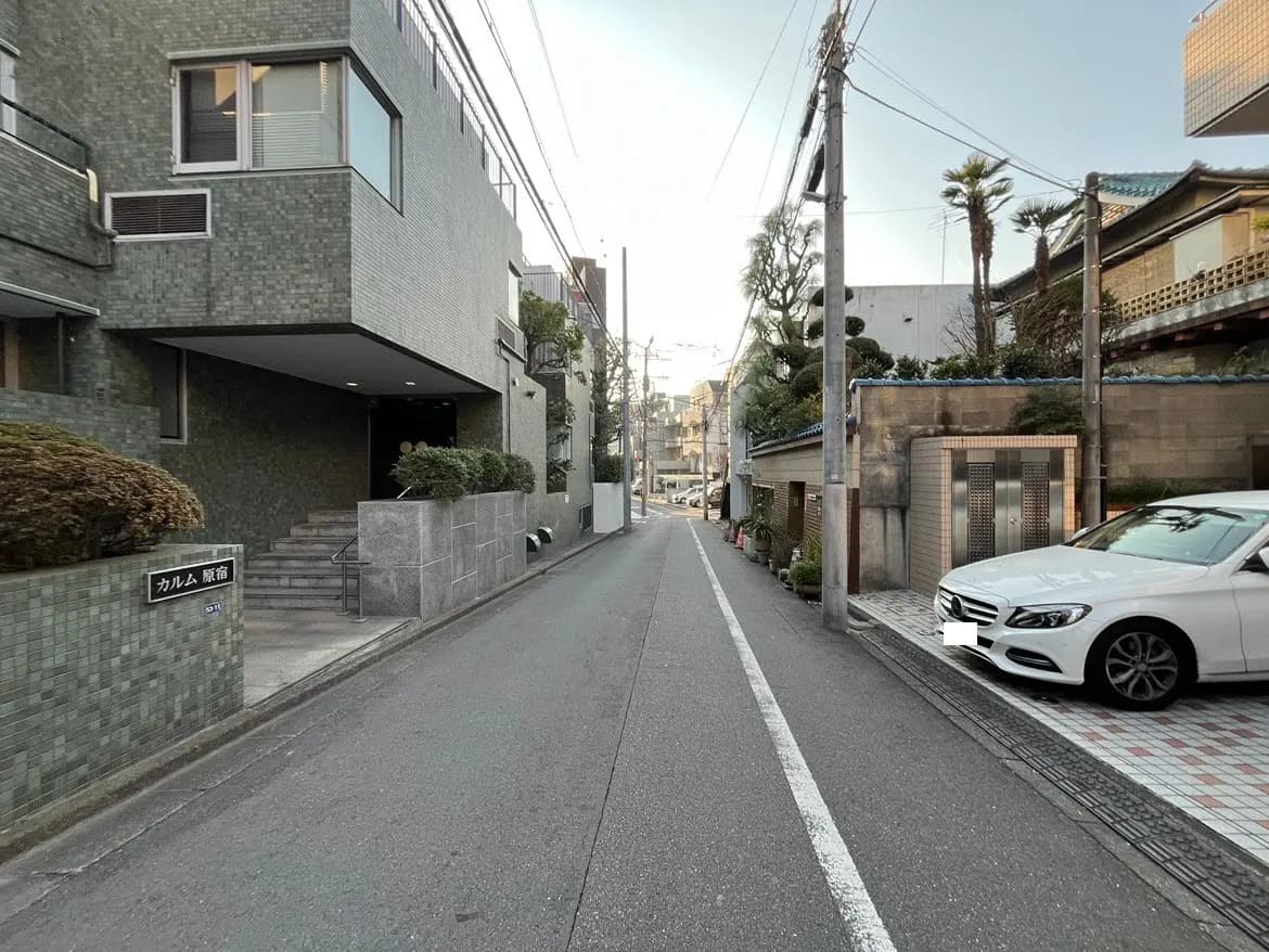 静かな住宅街の道路、近代的な建物と伝統的な家、駐車された車、夕方の街並み