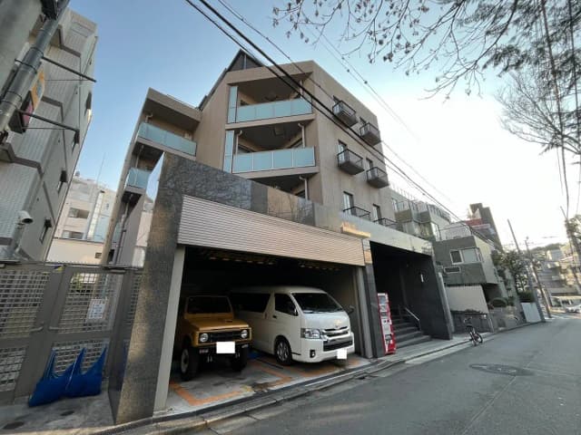 都市のマンション建物と地下駐車場、街路樹と歩道のある風景