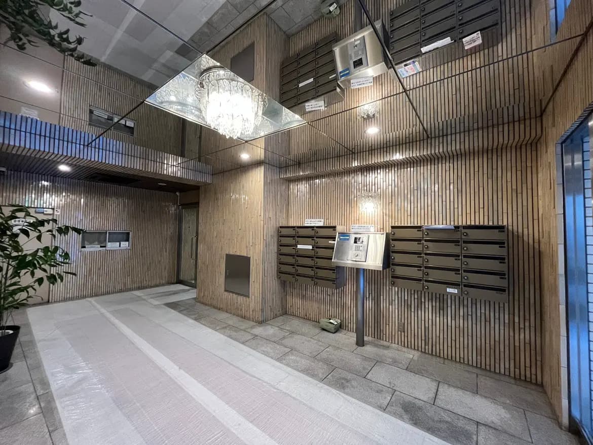 モダンなマンションのエントランスホール、木目調壁面、宅配ボックス、シックな照明設備