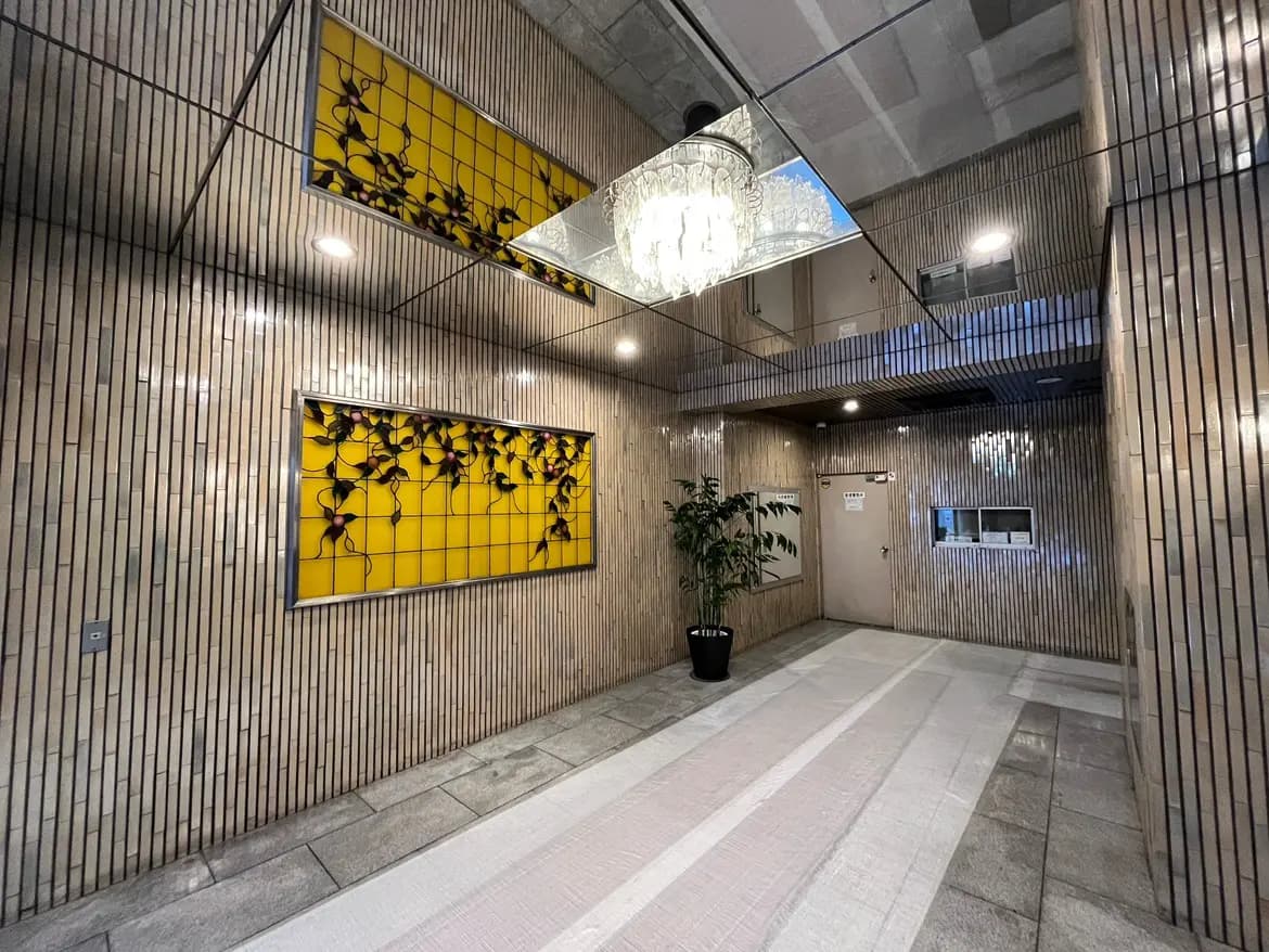 モダンなオフィスビルのエントランスホール、美しいシャンデリアとアート作品、木目調の壁装飾