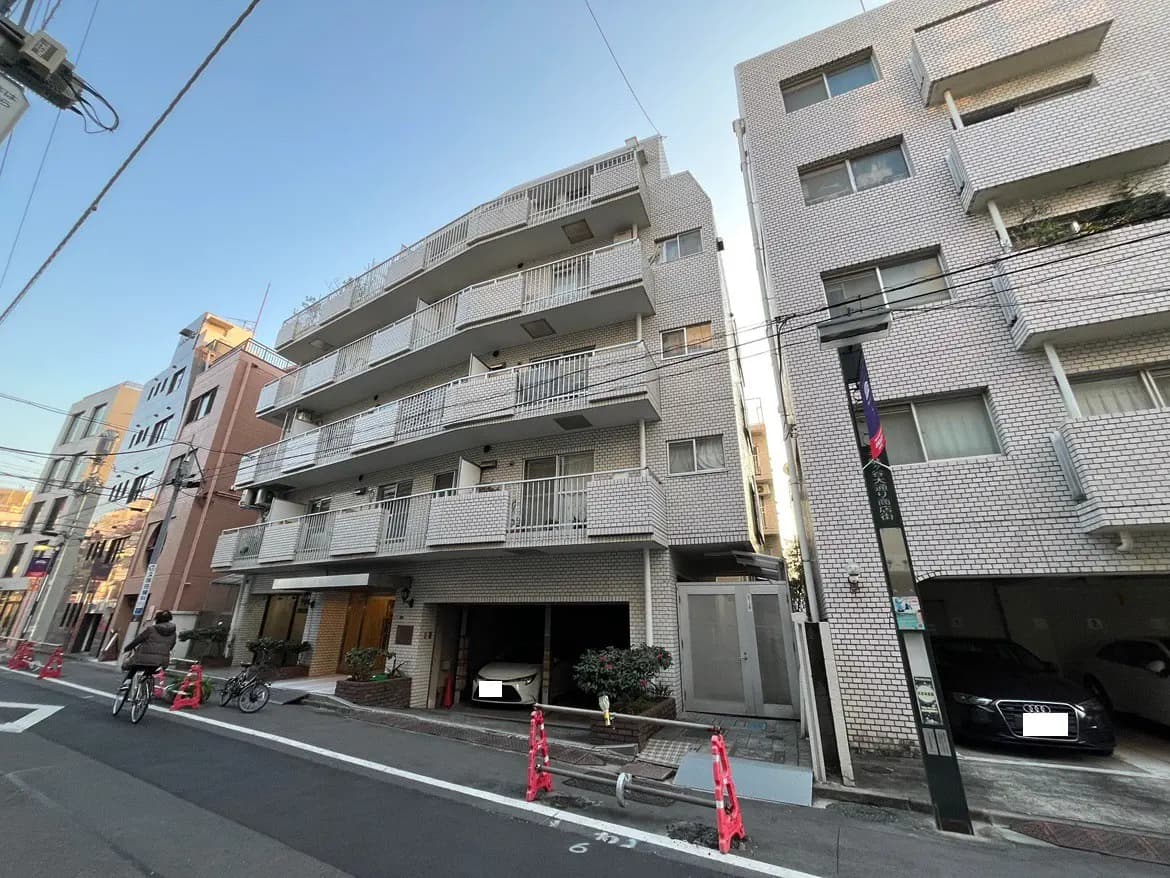 日本の住宅街にある白いタイル張りのアパート、自転車と駐車スペース付き