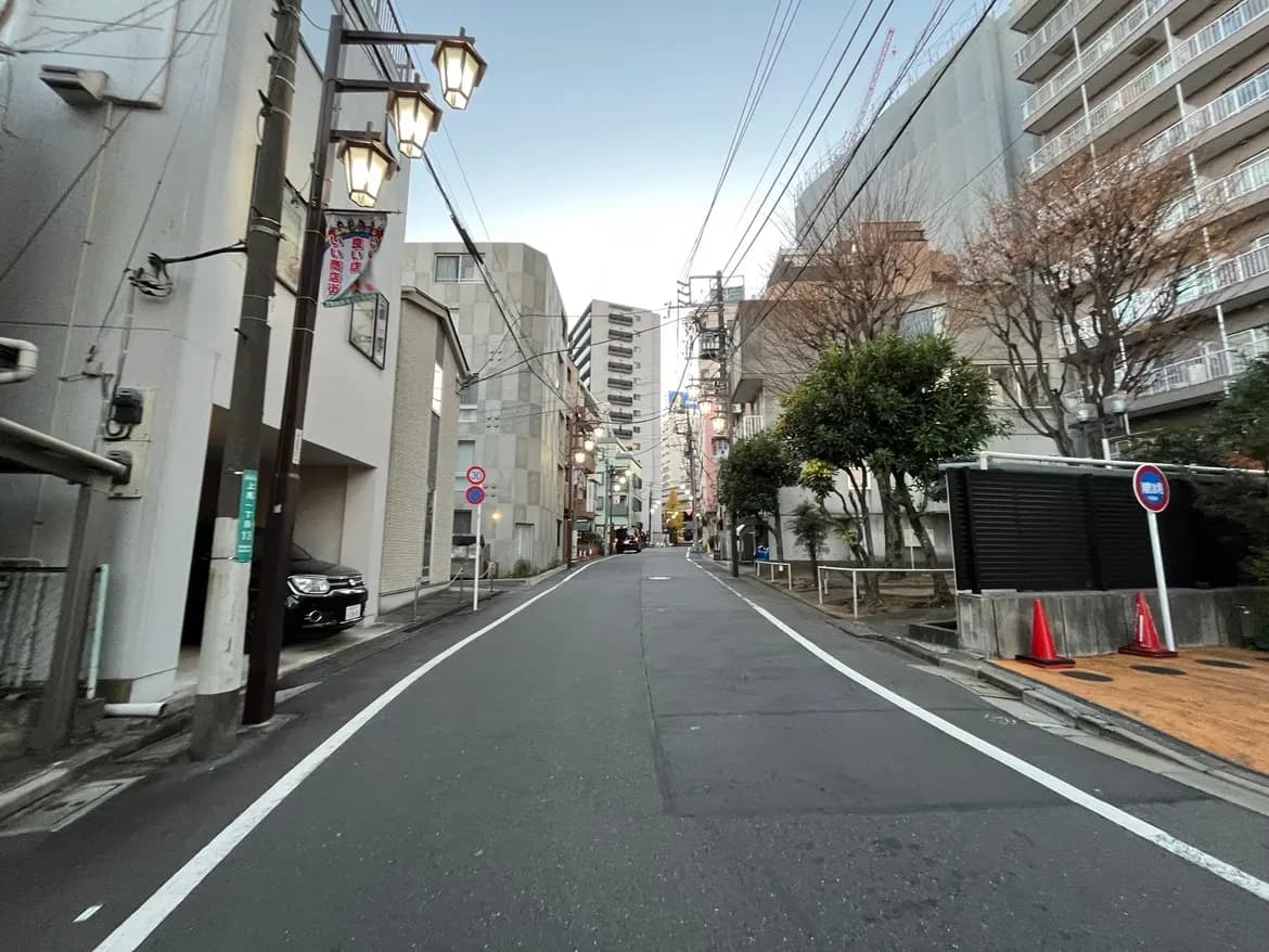 日本の都市の住宅街、早朝の静かな通り、ランプが灯る街灯とアパートメントの建物
