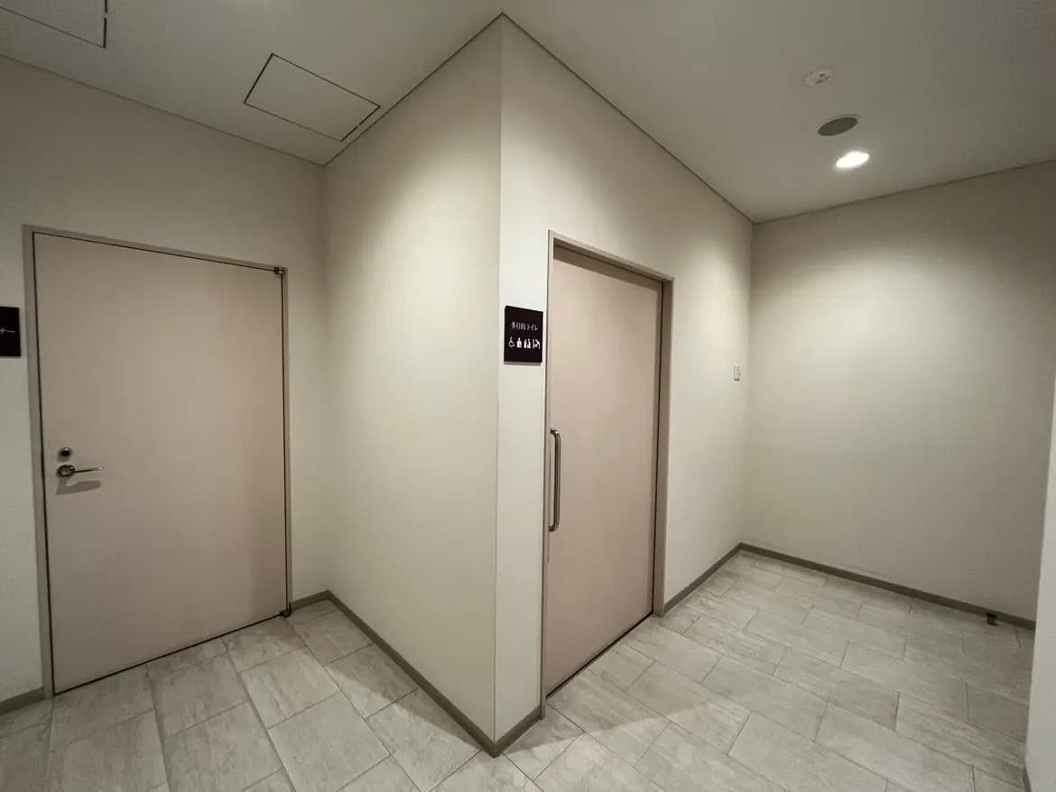 モダンな建物の共用廊下、清潔なタイルフローリング、配管スペースのある天井、灯り付き
