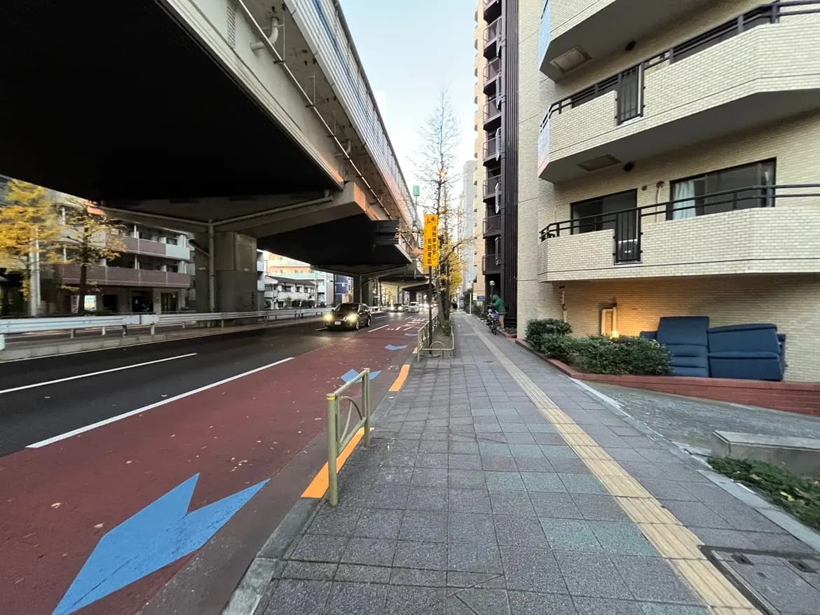 都市の歩道と自転車レーン、夕暮れ時のオフィスビルとマンション、高架下の通り