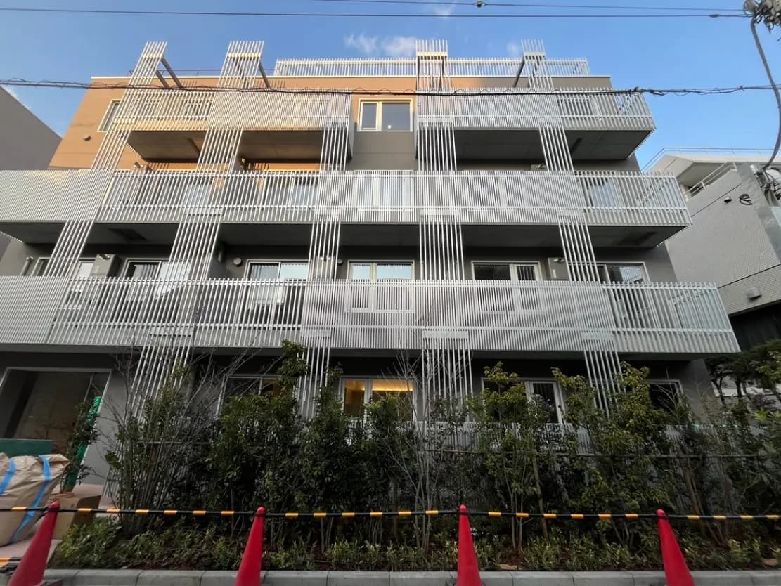 現代的な外観の都市型マンション、バルコニーに縦のラインデザイン、夕方の光が窓に映る