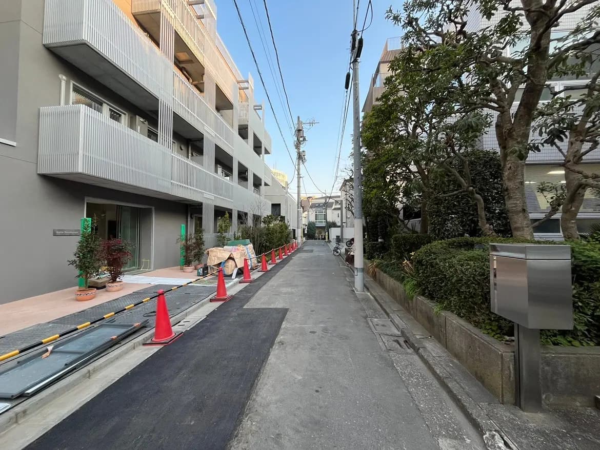 現代的な外観の住宅街、歩道と並木、工事中のアパートメント