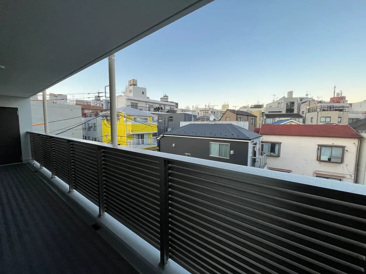 都市の風景を望むモダンなバルコニー、手すりと建物、青空