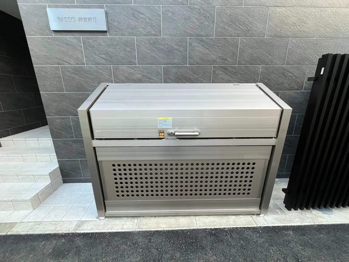 屋外に設置された現代的なデザインのゴミ箱、グレーのタイル壁と白い階段