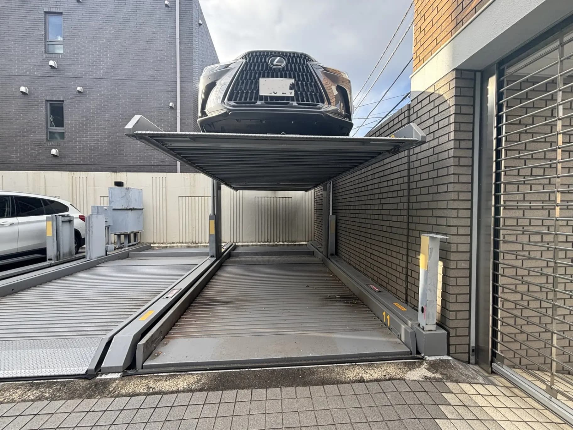 都市部の機械式駐車場のリフトに上がっている車、スペース節約の都市型パーキングソリューション