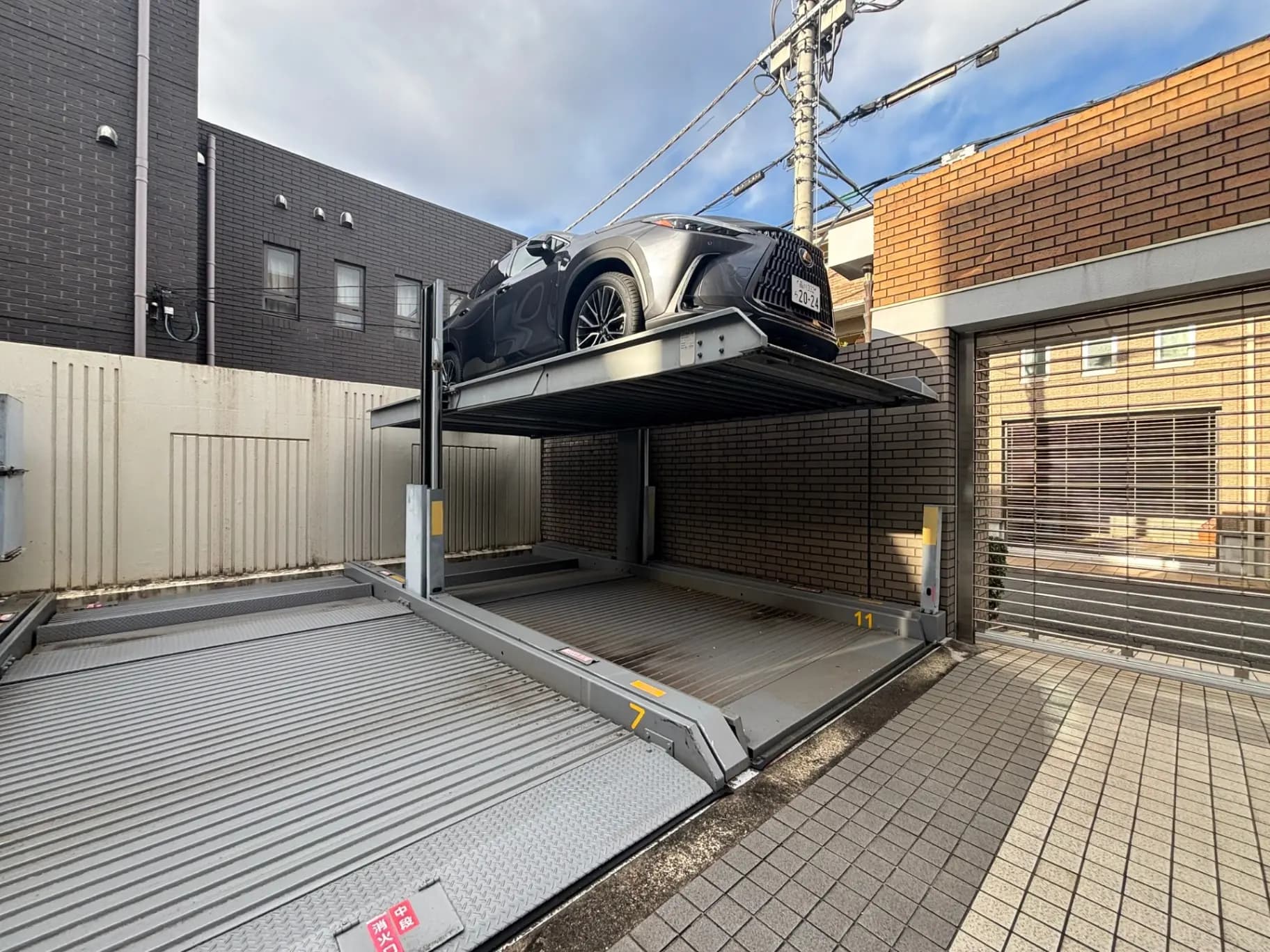 二段式駐車場のある都市の住宅街、上段にSUV車を駐車、日差しが照りつける昼間の光景