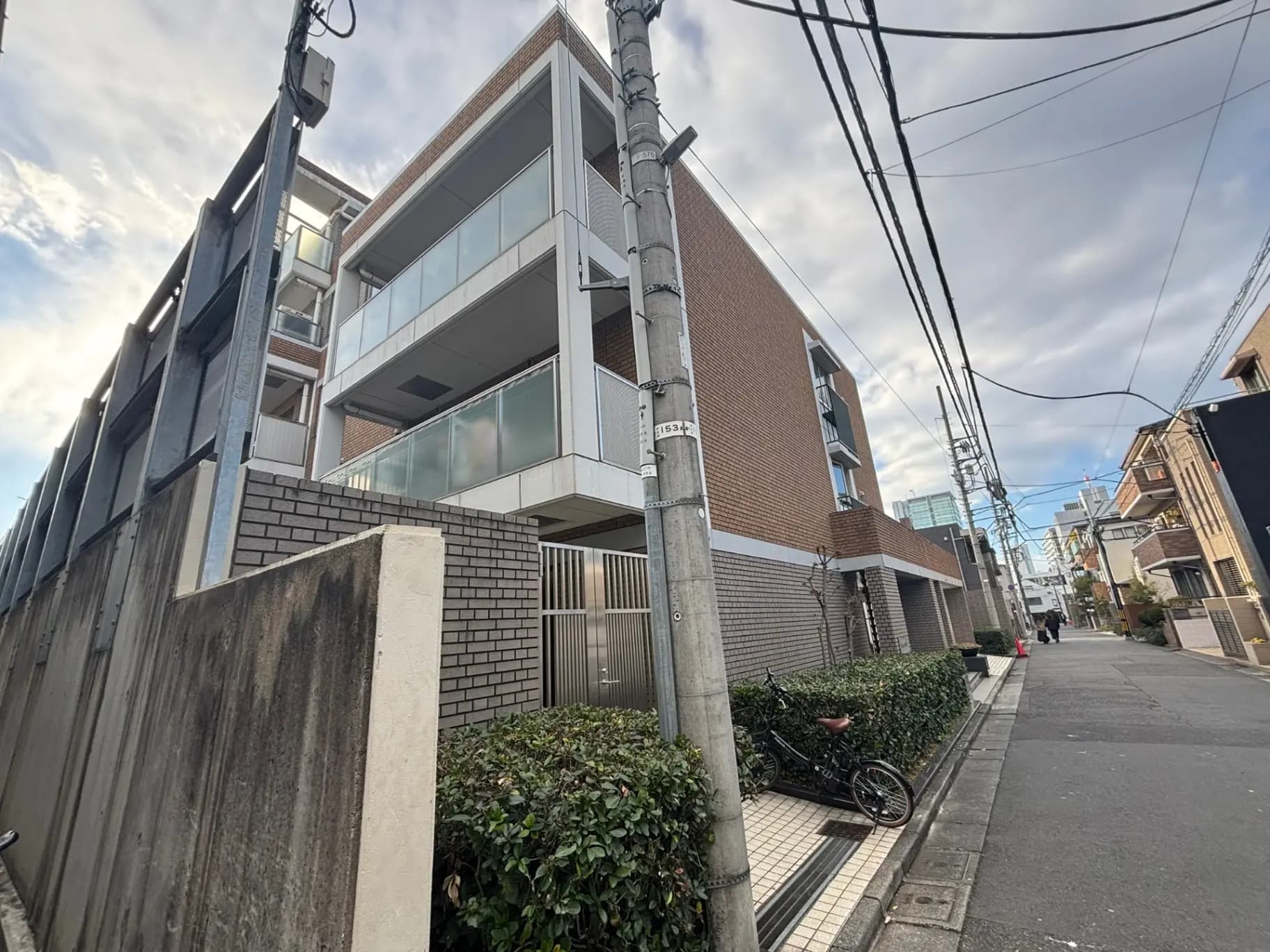 都市の住宅街にあるモダンな外観のビル、電柱と電線が見える通り