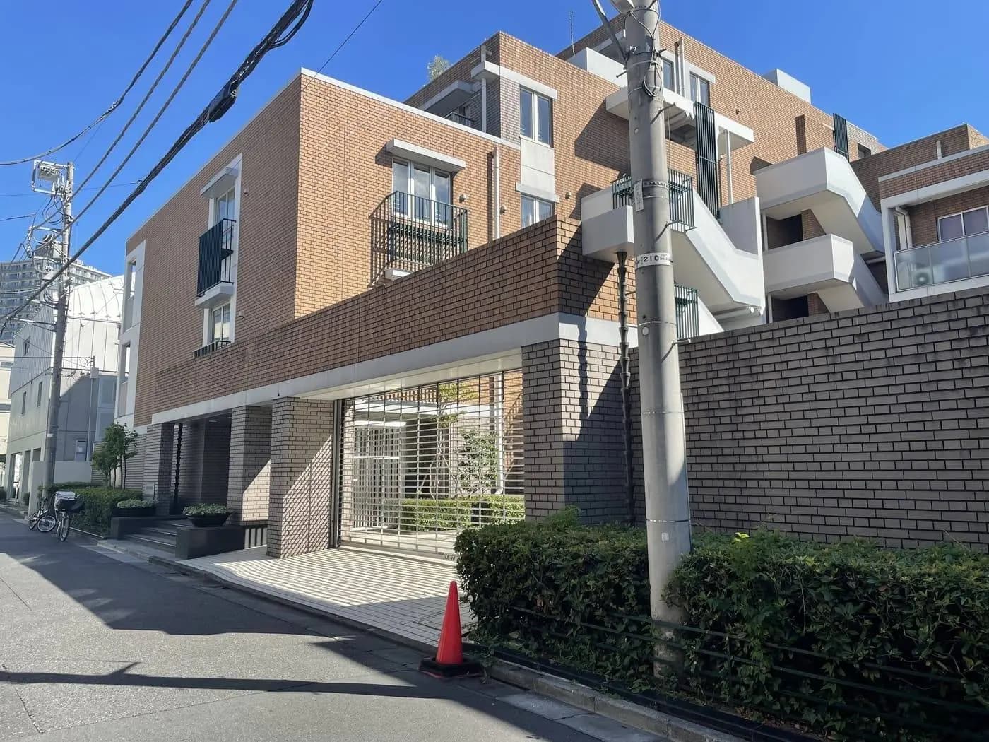 現代的な都市型マンション、クリーム色のレンガ壁、歩道と緑の植栽