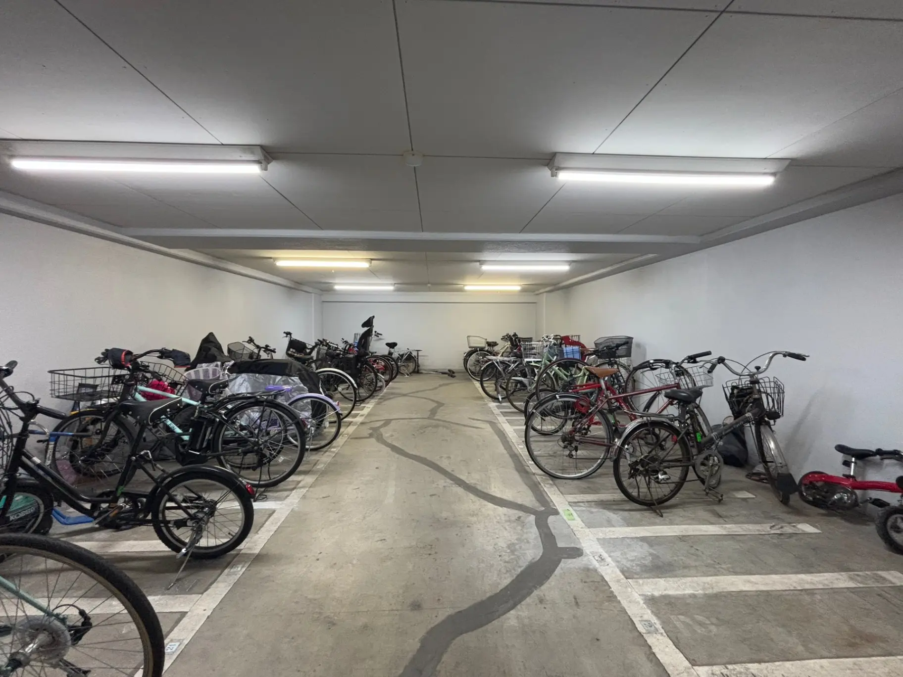 屋内の自転車駐輪場、整然と駐車された多数の自転車、清潔で明るいLED照明