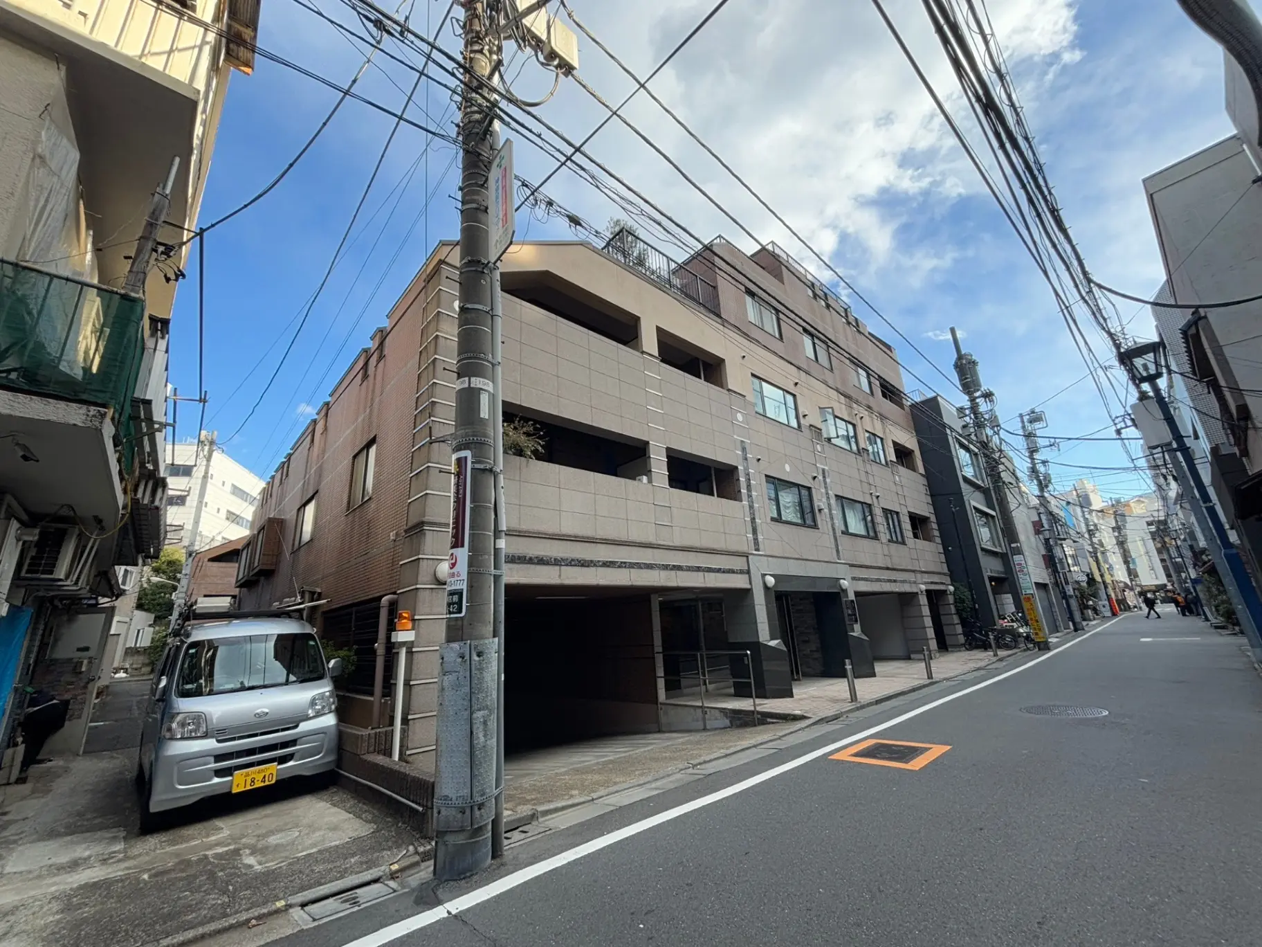 都市の日本の通り、電線が交差する空、建物のファサード、クルマが駐車している風景
