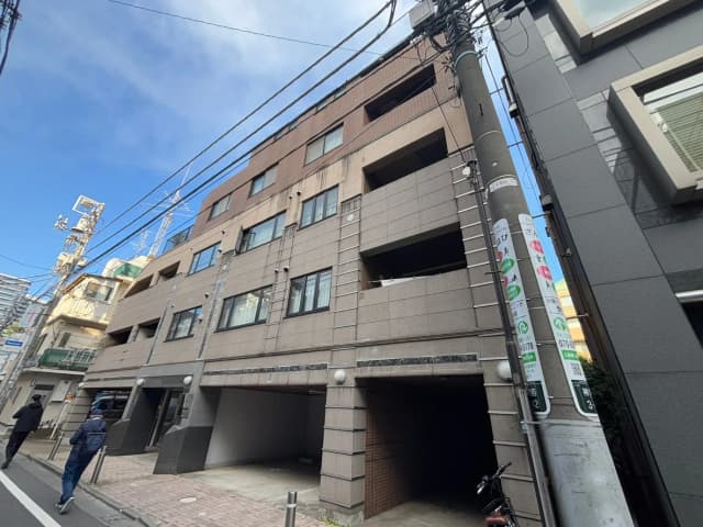 日本の都市のマンション外観、地上階にある駐車スペース、歩行者、背景に高電圧線