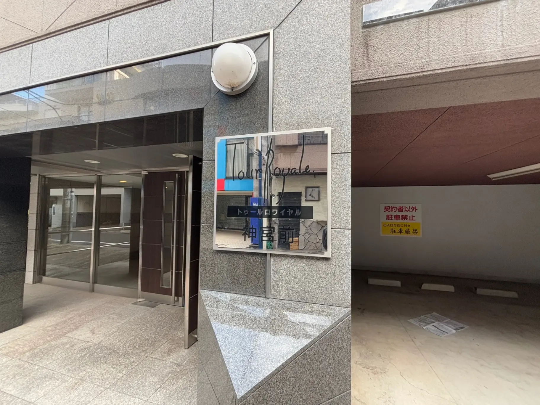 オフィスビルのエントランス、自動ガラスドアと反射する突き板、壁には案内図と衛生管理に関する掲示
