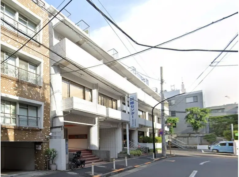 日本の都市部にある煉瓦造りのアパート外観、日差しが差し込む角地、地上に自転車駐輪スペースあり