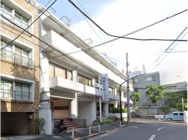 日本の都市部にある煉瓦造りのアパート外観、日差しが差し込む角地、地上に自転車駐輪スペースあり