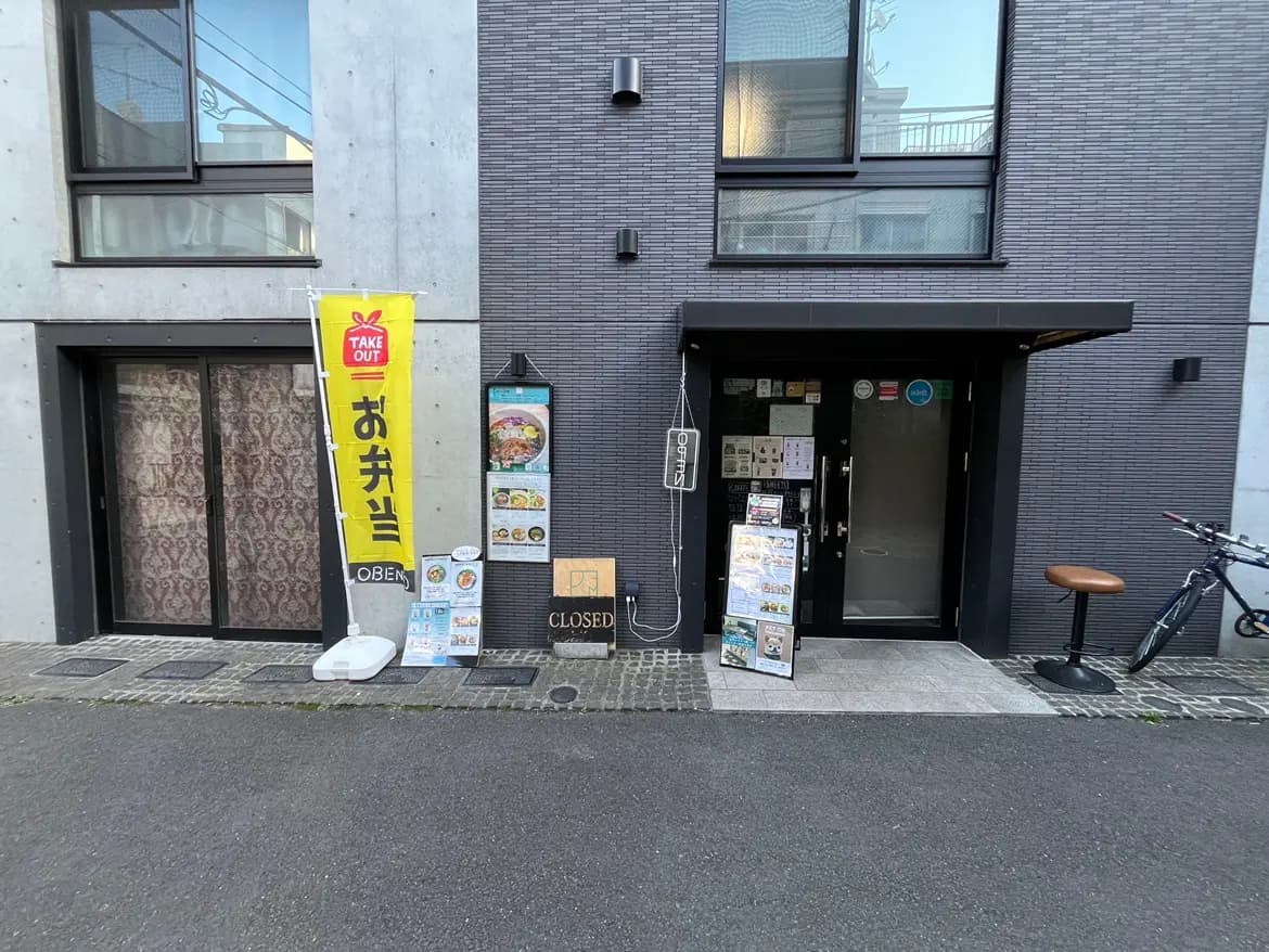 - お弁当のテイクアウト店の外観、黄色いのぼりとメニュー看板、閉店のサインが見える入り口の様子