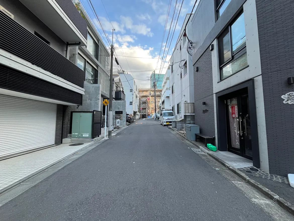 - 都市の静かな横道、モダンな建物が立ち並ぶ風景、青空が広がる日中の街並み