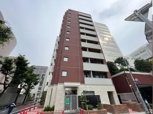- 都市型マンションの外観、モダンなデザインとバルコニー、周囲に緑の植栽がある街の風景