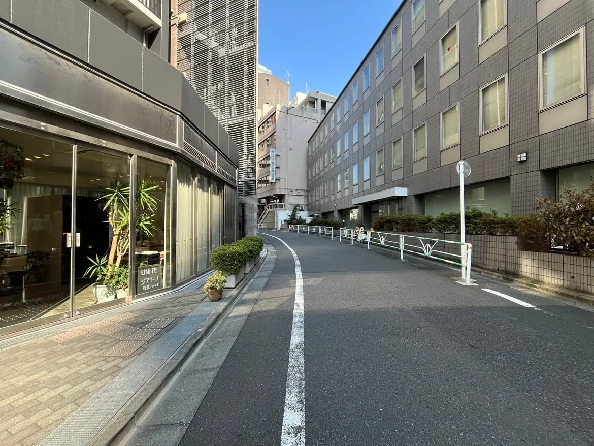 - 都市の風景、曲がりくねった道路とガラス張りの建物、歩道には植栽が施されたエリア