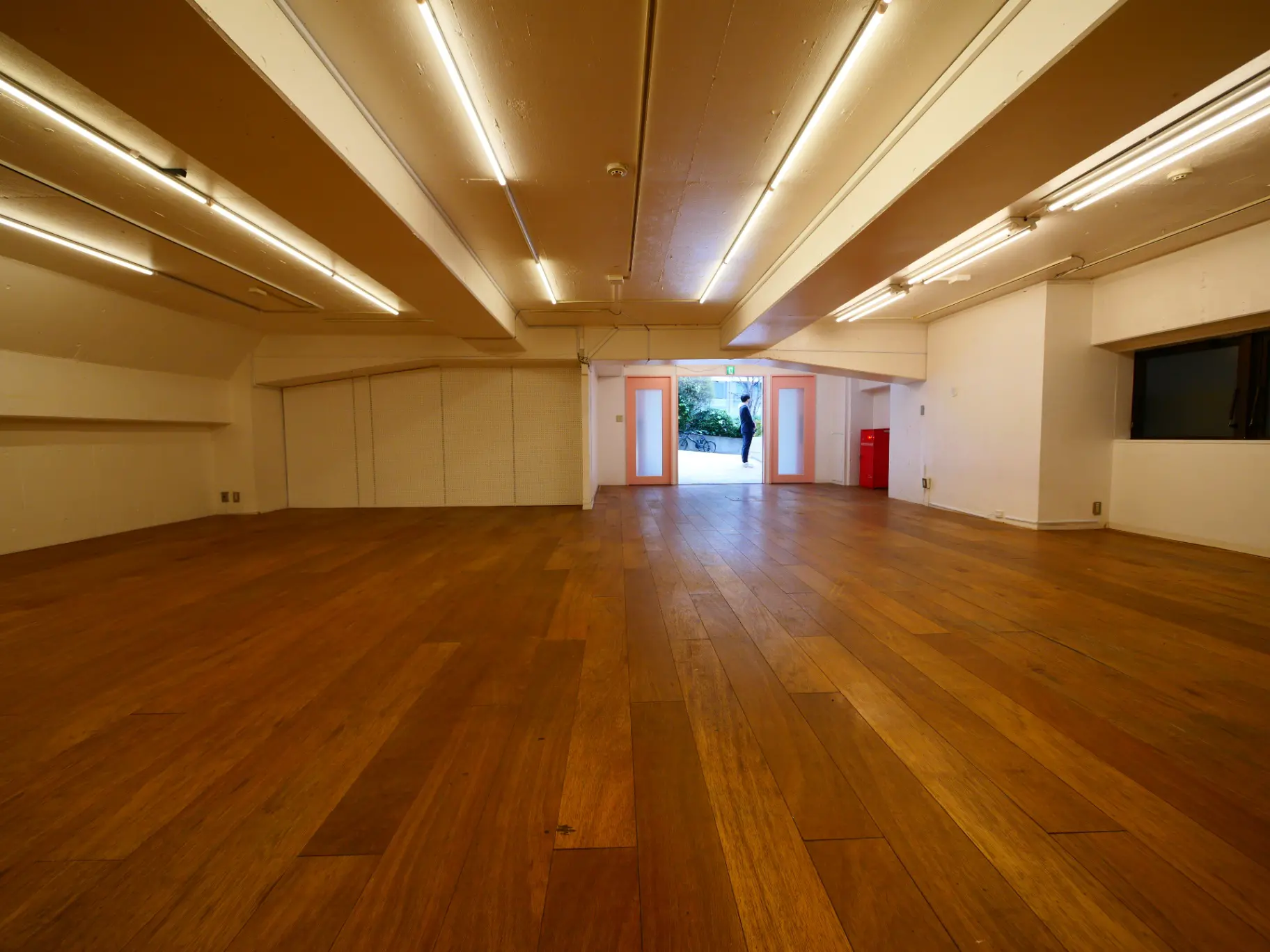 広々としたダンススタジオやイベントホール、木製のフローリング、白い壁、長い蛍光灯が設置されているインテリア