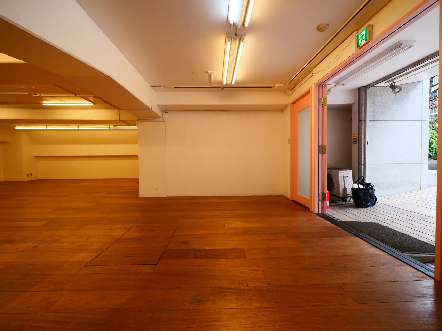 広々とした木製フローリングの会議室や多目的スペース、天井には長い蛍光灯が設置