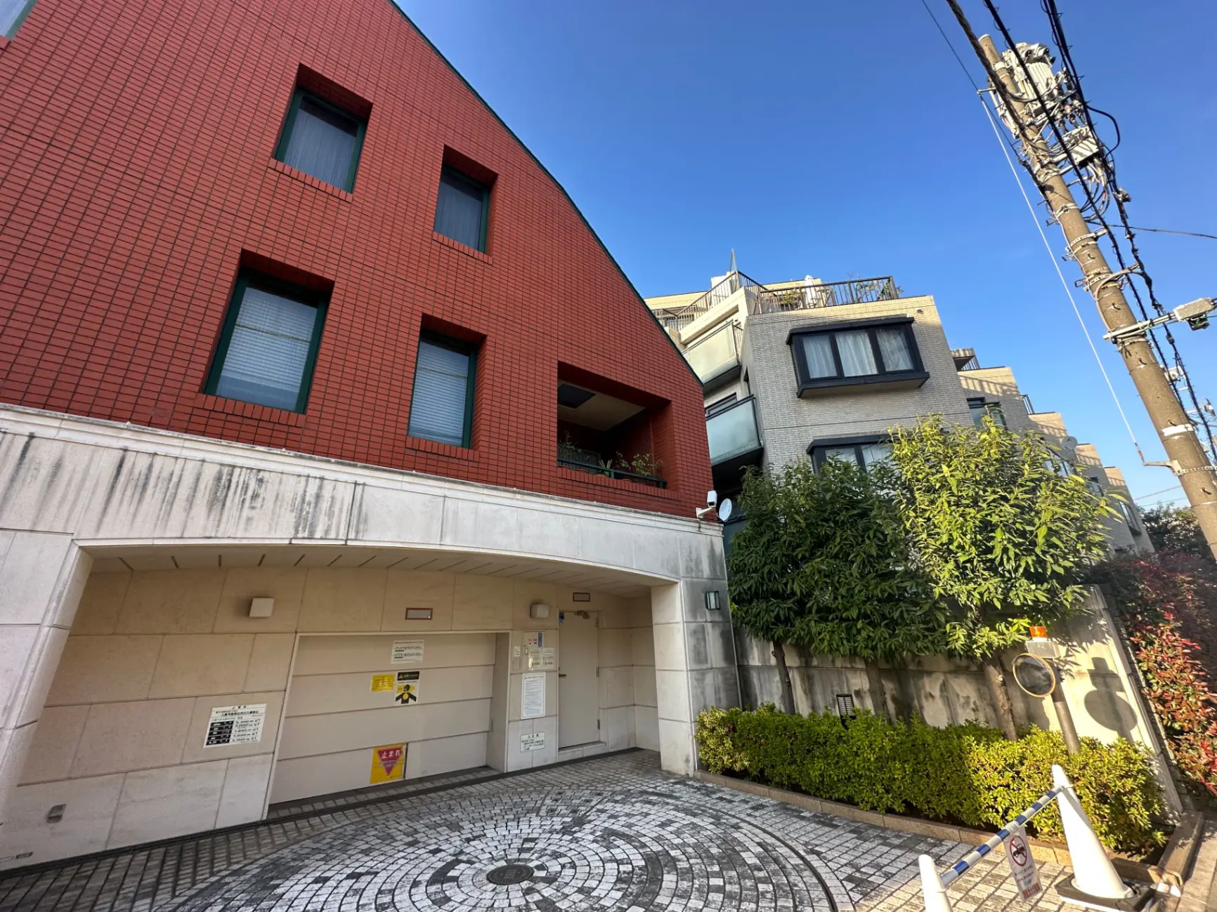 都市の住宅街にあるレンガの外壁が特徴的な現代建築のマンション、洗練されたエントランスと石畳の歩道