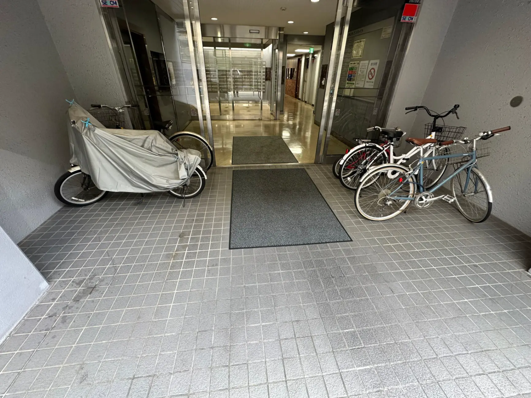 アパートのエントランスに置かれた自転車、タイルの床、清潔で整備された共有スペース