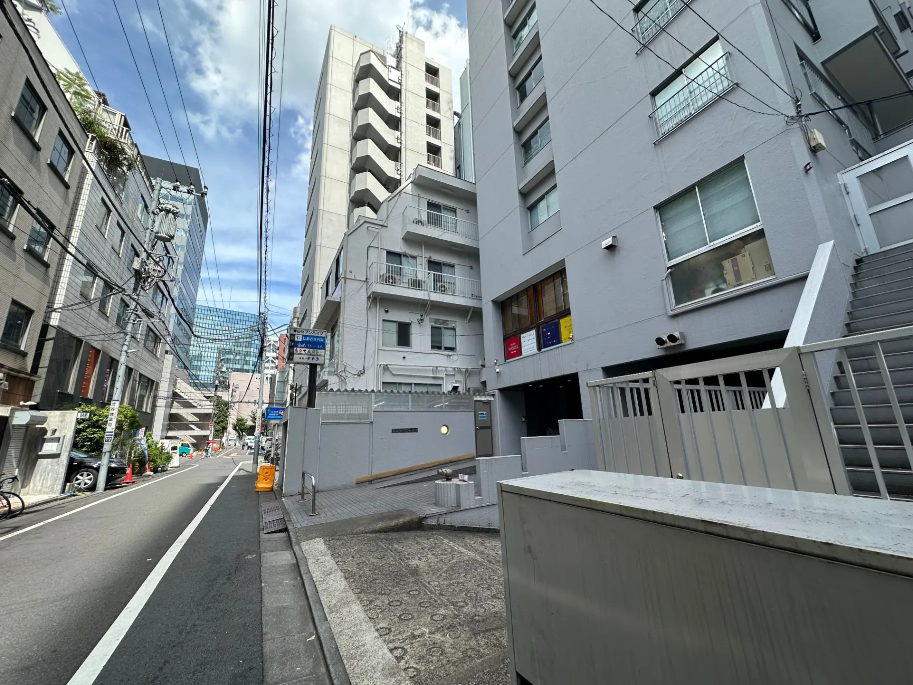 都市の日常風景、電線が走る狭い道路、近代的なビルと住宅、晴れた日の明るい街角