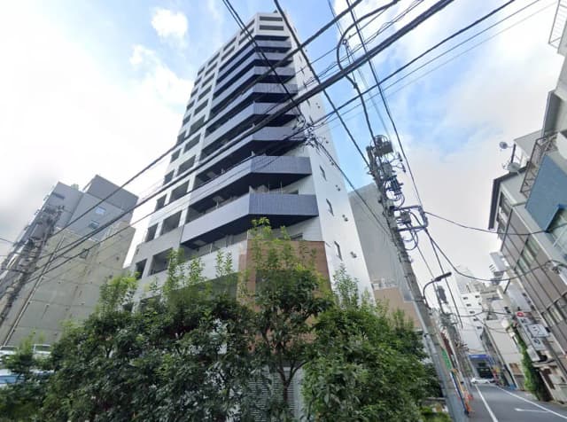 - 高層マンションの外観、近くに電柱と緑の生い茂る植栽がある都市の風景