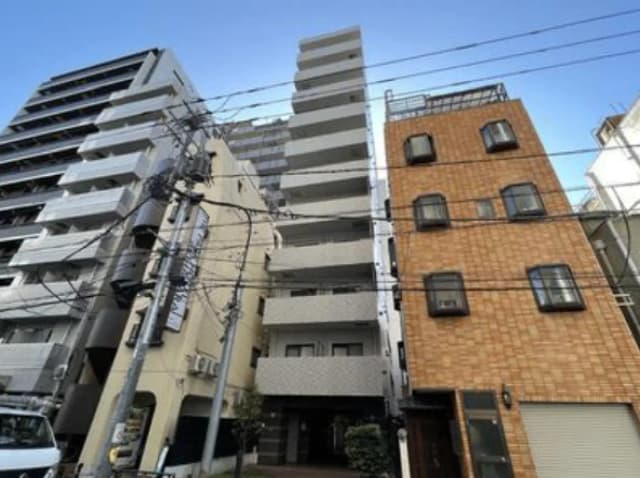 - 都市型マンションの外観、モダンなデザインの高層ビルと隣接する趣のあるレンガ造りの建物、電線が交差する街景色