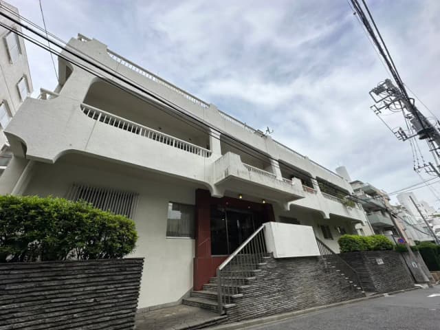 ユニークなデザインの都市型集合住宅、外観に特徴的な曲線と階段、電柱と青空