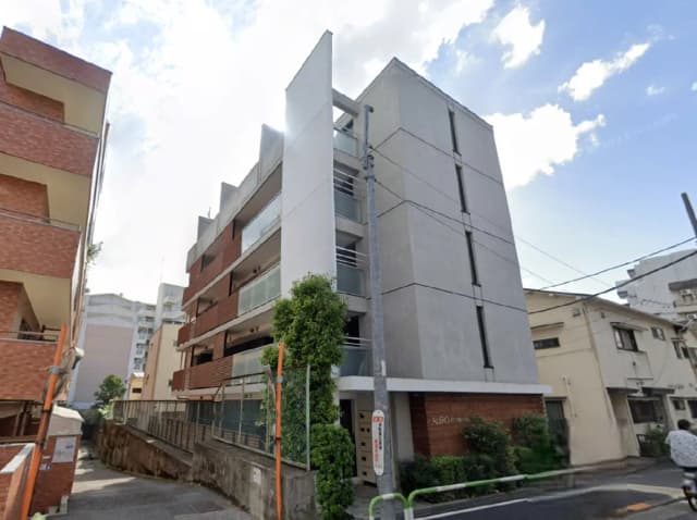 - モダンなデザインのアパートメントビル、隣接するレンガ造りの建物と緑の植栽がある外観