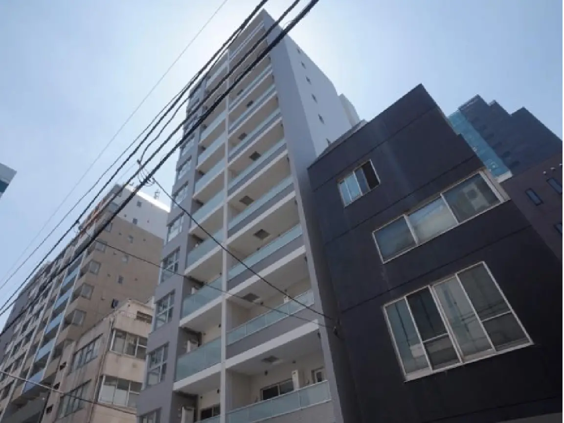 - 高層ビルの外観、青空をバックにした現代的なデザインのマンション、周囲には他の建物や電線が見えるシーン