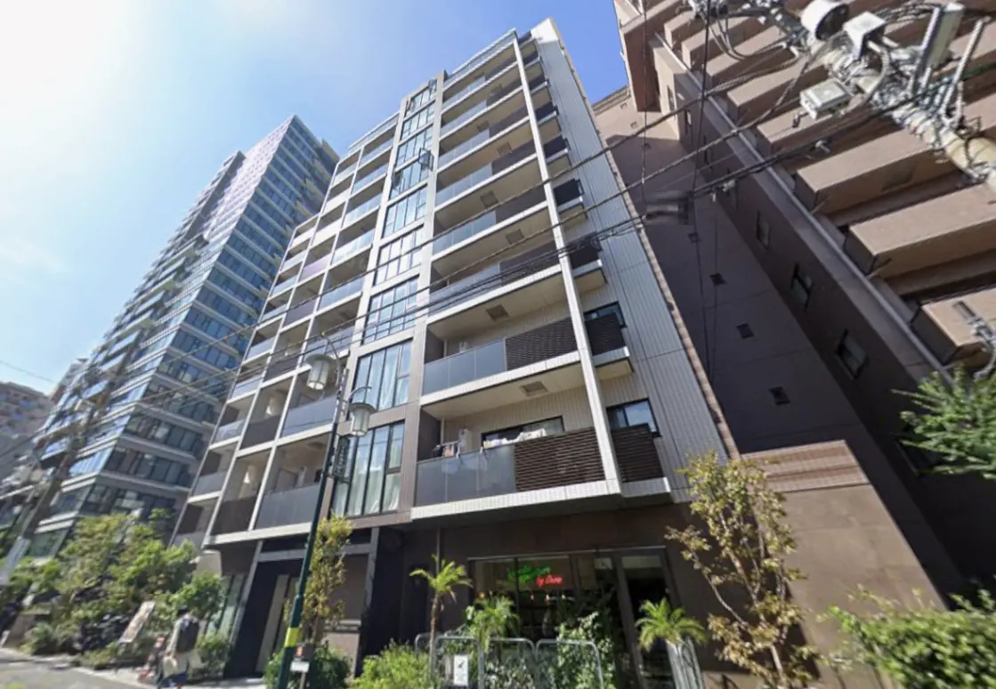 - 近代的な外観のマンション、ガラスバルコニーとスリムなデザイン、青空と街路樹が映える都市の風景