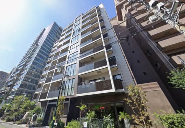 - 近代的な外観のマンション、ガラスバルコニーとスリムなデザイン、青空と街路樹が映える都市の風景