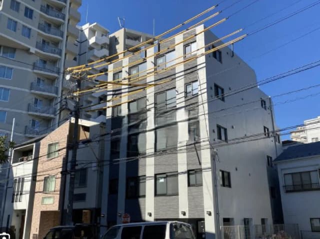 - 都市の景観に立つ現代的なアパートビル、コンクリートとガラスのファサード、青い空を背景にした建物の外観