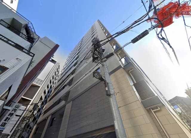 日本の都市部にある現代的な建物の外観、青空の下に電柱と電線が交差する景観