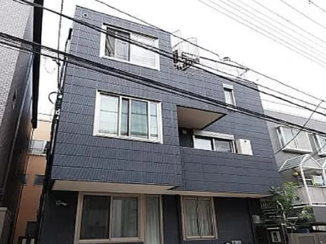 - モダンなデザインの三階建てのアパートメント、グレーの外壁と大きな窓、隣接する建物との距離感が特徴的な景観