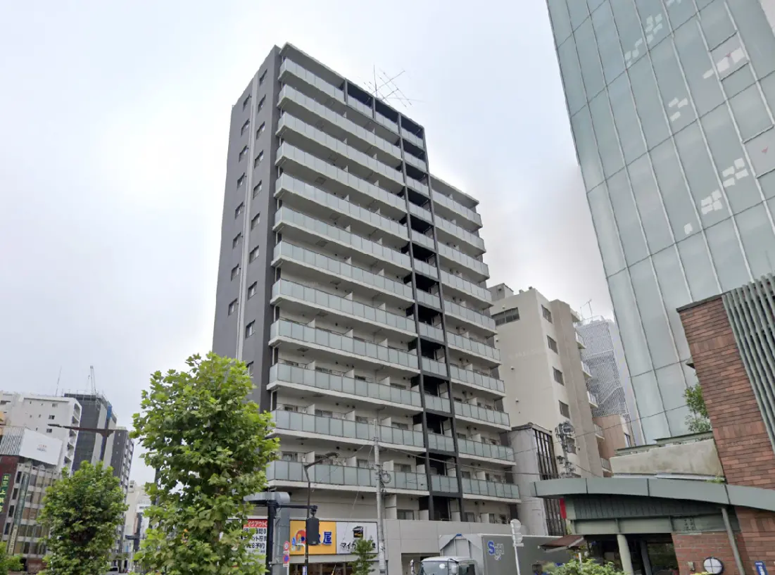 - モダンなデザインの集合住宅、バルコニー付きの階層構造、周囲に都市景観が広がる外観